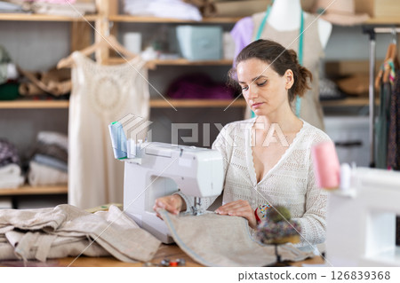Female seamstress working on sewing machine in workshop 126839368