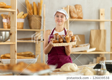 Teen girl holding croissants in square wicker basket Teen girl holding croissants in square wicker basket 126839538