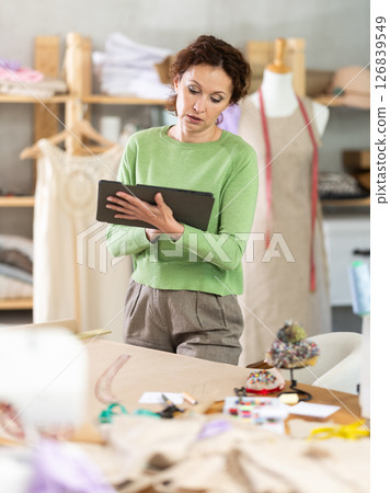 Woman tailor creates sketch of dress on tablet Woman tailor creates sketch of dress on tablet 126839549