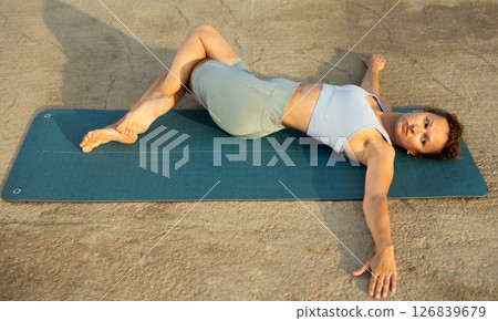 Yoga practice on embankment, female athlete fulfil carry out Adho Mukha Svanasana Yoga practice on embankment, female athlete fulfil carry out Adho Mukha Svanasana 126839679