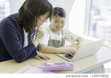 Elementary school girl and teacher studying on a laptop at a cram school. Photo courtesy of Tokyo Electronics College of Denpa Gakuen, a private school corporation. Elementary school girl and teacher studying on a laptop at a cram school. Photo courtesy of Tokyo Electronics College of Denpa Gakuen, a private school corporation. 126839930
