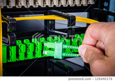 Hand of computer engineer connecting fiber optic cable in server Hand of computer engineer connecting fiber optic cable in server 126840178