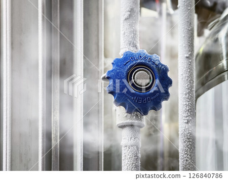 A close-up of a blue valve with nitrogen frost, indicating low temperatures in industrial conditions A close-up of a blue valve with nitrogen frost, indicating low temperatures in industrial conditions 126840786