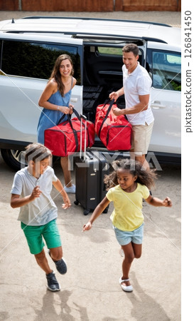 Family Loading Suitcases into Minivan for Road Trip 126841450