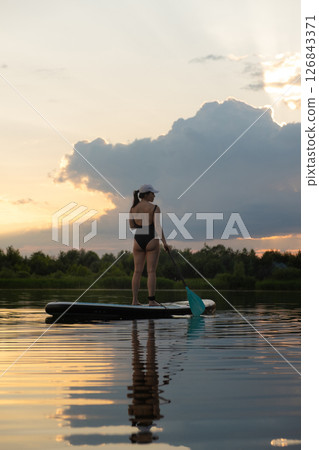 Paddleboarding at Sunset on a Tranquil Lake Paddleboarding at Sunset on a Tranquil Lake 126843371