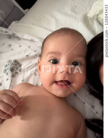 Smiling Baby on Floral Sheets 126843433
