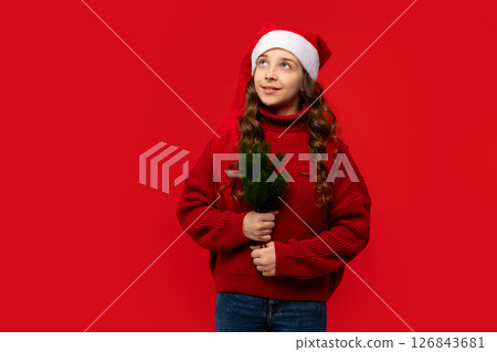Teen girl in Santa hat holding small green fir branches. 126843681