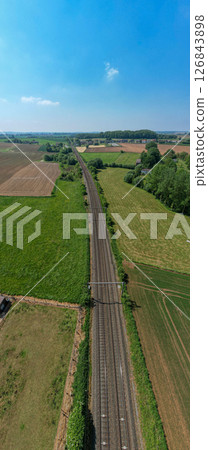 Aerial View of Train Tracks Beautifully Surrounded by Lush Green Fields of Agriculture Aerial View of Train Tracks Beautifully Surrounded by Lush Green Fields of Agriculture 126843898