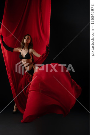 Model showcasing elegance with red fabric in a dramatic casting session 126843978