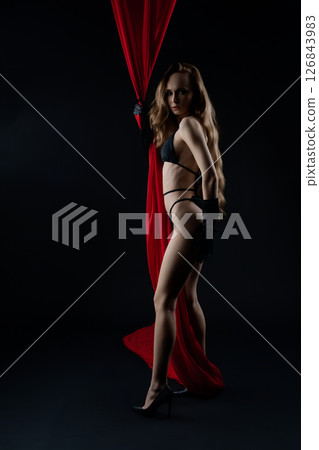 Model poses elegantly with red curtain in dramatic casting setting Model poses elegantly with red curtain in dramatic casting setting 126843983