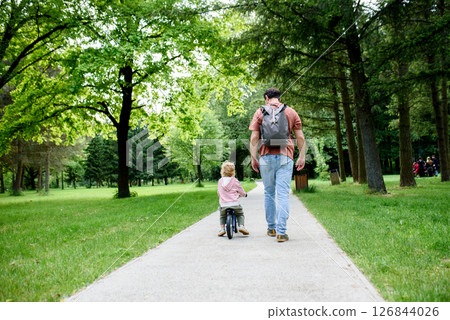 Rear view of father walking with his son across park Rear view of father walking with his son across park 126844026