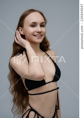A woman with long hair poses confidently in minimal swimwear for a casting call 126844047