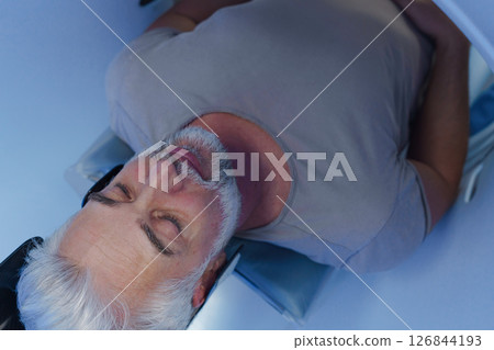 Male patient undergoing CT scan examination in hospital. 126844193