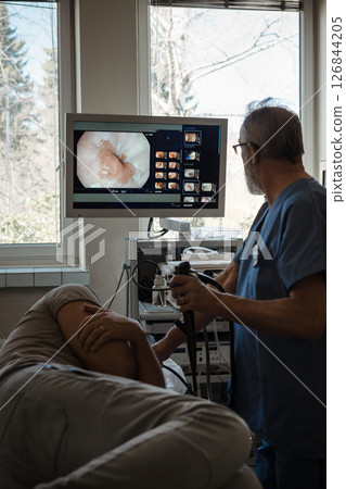 Doctor looking at monitior during gastroscopy procedure, examining upper digestive tract. Doctor looking at monitior during gastroscopy procedure, examining upper digestive tract. 126844205