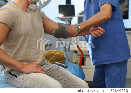 Doctor taking patient's blood pressure using digital blood pressure monitor. Doctor taking patient's blood pressure using digital blood pressure monitor. 126844210