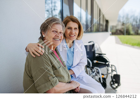 Elderly patient talking with caring female physician in front of hospital. 126844212