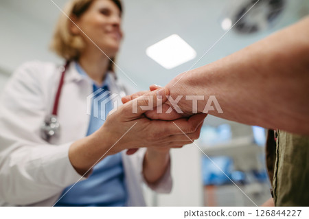 Caring doctor holding senior patient hand. 126844227