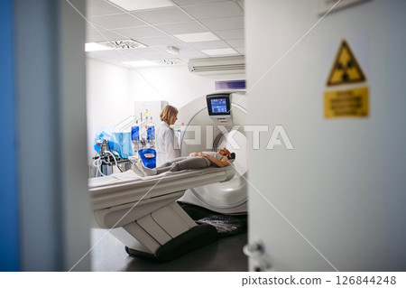 Doctor operating CT machine and preparing patient for scan 126844248
