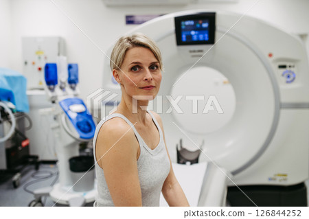 Woman sitting on CT scanner bed, waiting for examination 126844252