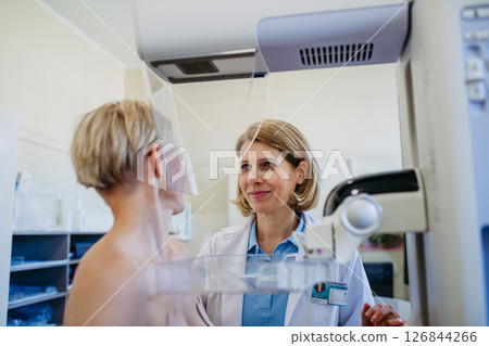 Healthcare professional adjusts the patient for accurate breast imaging. Healthcare professional adjusts the patient for accurate breast imaging. 126844266