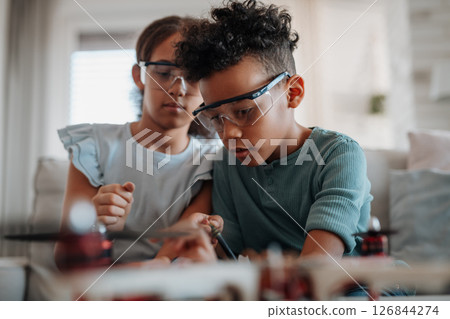 Classmates assembling robotic kit, working with circuit board at home. Classmates assembling robotic kit, working with circuit board at home. 126844274