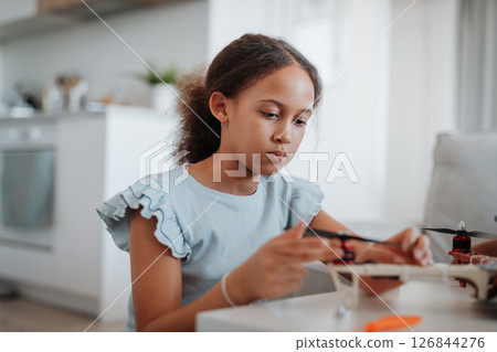 Focused girl working on small robot toy at home. 126844276