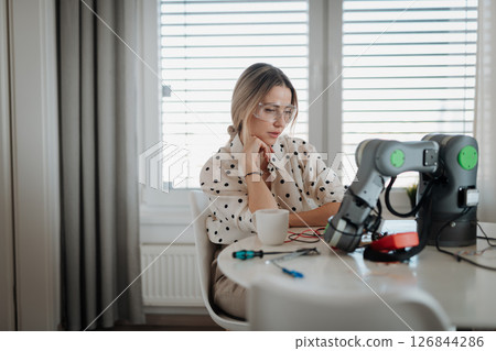 Woman engineer working on robotic arm project at home. Woman engineer working on robotic arm project at home. 126844286