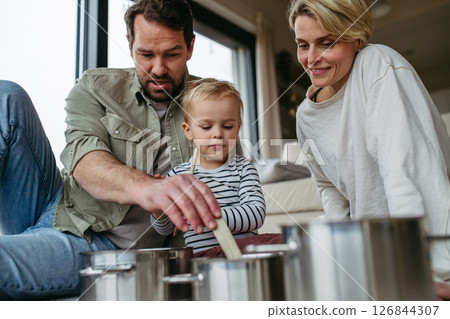Parents and toddler son playing drums on kitchen pots Parents and toddler son playing drums on kitchen pots 126844307