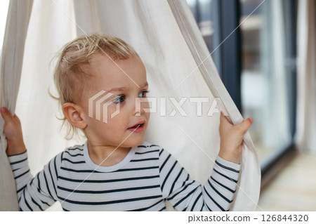 Adorable toddler boy playing hide and seek. Adorable toddler boy playing hide and seek. 126844320