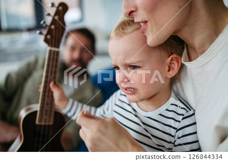 Little boy holding guitar, learning to play. 126844334