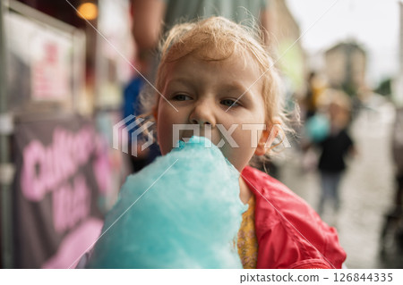 Cute kid eating cotton candy outdoors Cute kid eating cotton candy outdoors 126844335