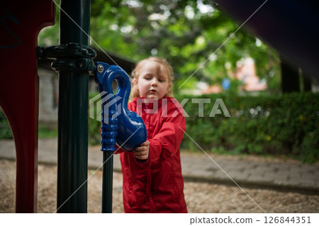 Child in red raincoat spending free time on playground 126844351