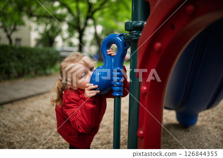 Curious girl peeking through playground tube 126844355