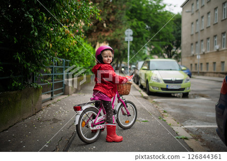 Little girl riding pink bike with basket, wearing helmet. Little girl riding pink bike with basket, wearing helmet. 126844361