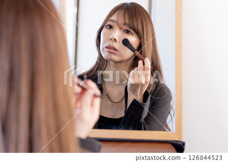 Woman doing self-makeup① Woman doing self-makeup① 126844523