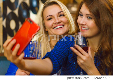 Girls in pub club taking self photo with phone 126844802