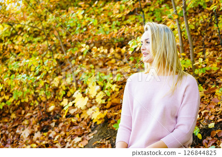 Blonde woman relaxing in autumn park Blonde woman relaxing in autumn park 126844825