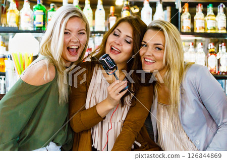 Women in bar singing karaoke Women in bar singing karaoke 126844869