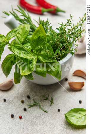 Fresh herbs and spices in mortar with pestle on kitchen table 126845213
