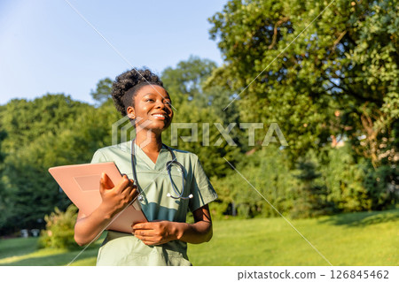 Smiling dark-skinned woman in a lab coat on a greenery background 126845462