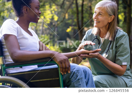 Nurse doing rehabilitation exercises with an african american female patient in the park 126845556