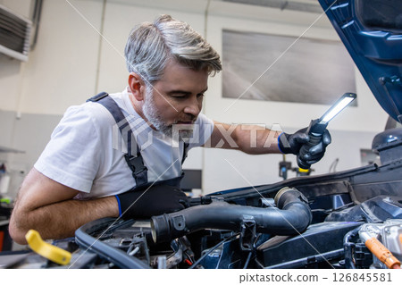 Mechanic inspecting engine with flashlight Mechanic inspecting engine with flashlight 126845581