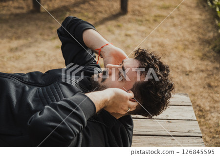 Man Trains on a Wooden Bench in the Outdoor Park 126845595