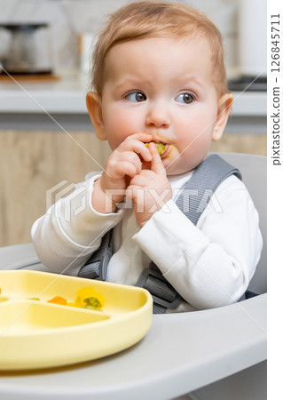 Portrait of a cute small baby boy looking aside while sitting on his chair 126845711