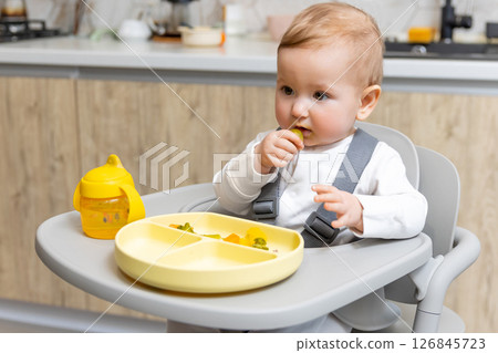 Sweet caucasian baby boy making breakfast while sitting on his chair Sweet caucasian baby boy making breakfast while sitting on his chair 126845723