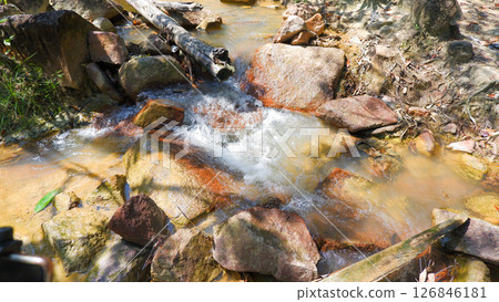Clear Stream Flowing Over Colorful Rocks in Tropical Forest Clear Stream Flowing Over Colorful Rocks in Tropical Forest 126846181
