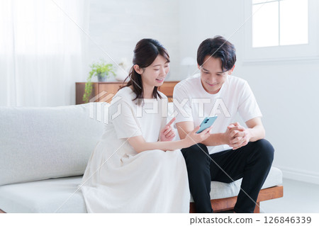 Pregnant wife and husband looking at smartphone 126846339