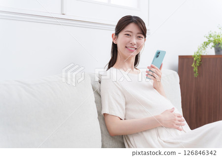 Smiling pregnant woman using a smartphone 126846342