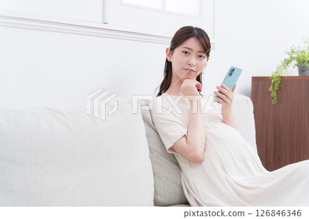 Pregnant woman using a smartphone (worrying/thinking) Pregnant woman using a smartphone (worrying/thinking) 126846346