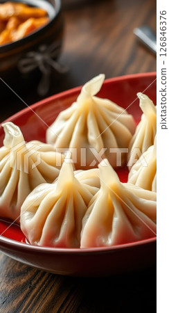 Dumplings arranged beautifully on a red plate, showcasing traditional cuisine in a cozy setting 126846376